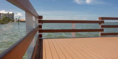 Composite wood dock with dark wood railing on the water.