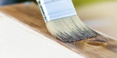 Brush painting medium stain onto a sanded wooden plank
