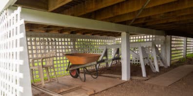 Under deck storage space with lattice fence wall. Storage for a wheelbarrow, saw horses, and a chair