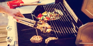 Outdoor deck grill with meat and vegetables.