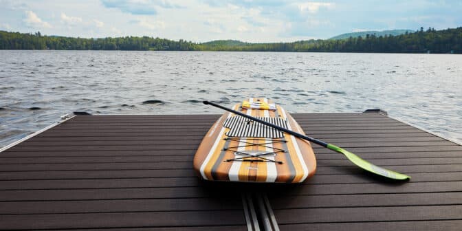 seaside decking resistant to salt with stand up paddleboard facing large body of water